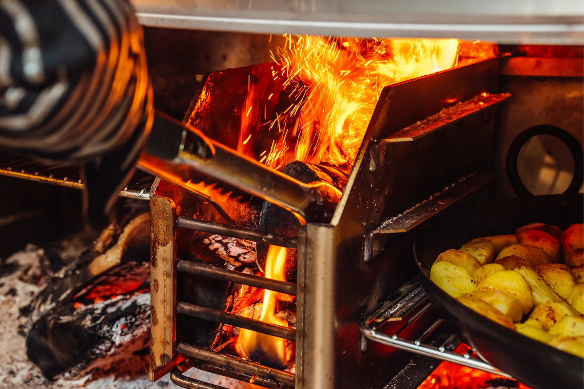 Flames in the oak fire grill with potatoes roasting