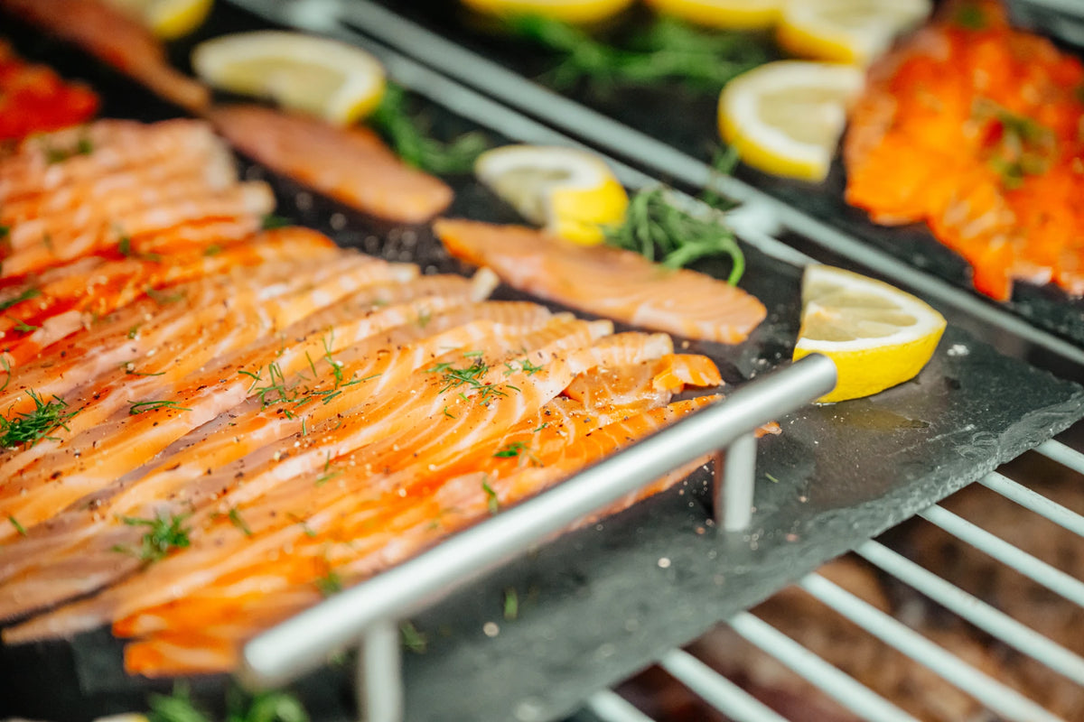 Smoked salmon laid out on slate with lemon and dill