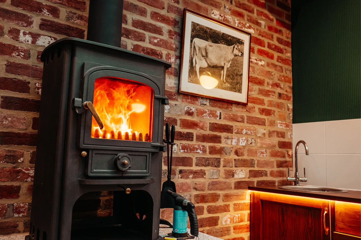 The wood burner glowing against the brick wall